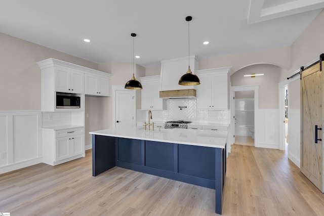 kitchen featuring built in microwave, white cabinetry, decorative backsplash, and a barn door