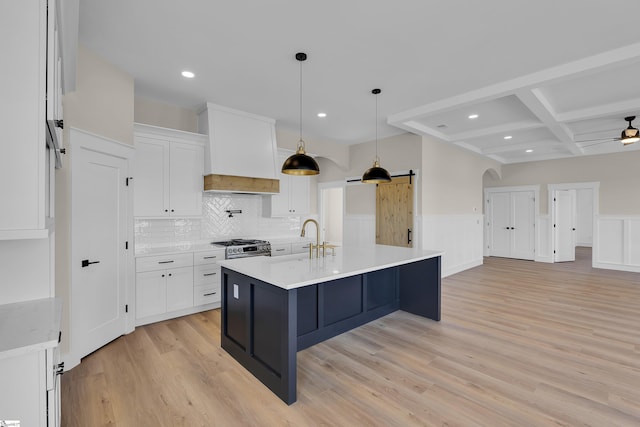 kitchen featuring a barn door, white cabinetry, light countertops, and premium range hood