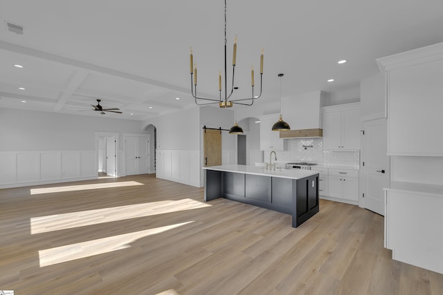 kitchen with arched walkways, a barn door, premium range hood, visible vents, and light countertops