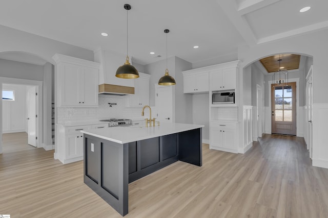 kitchen with arched walkways, white cabinets, and built in microwave