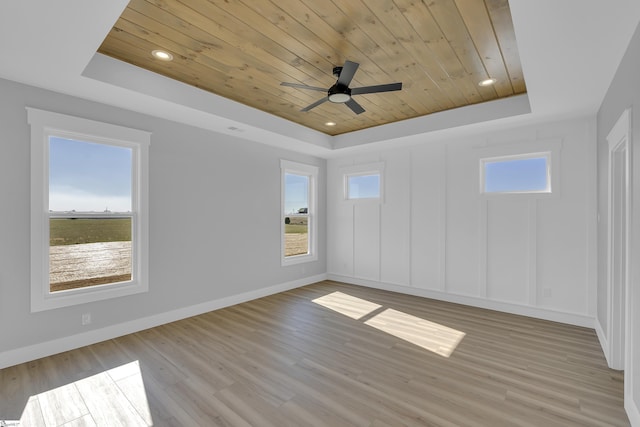 unfurnished room featuring a raised ceiling, wooden ceiling, and a healthy amount of sunlight