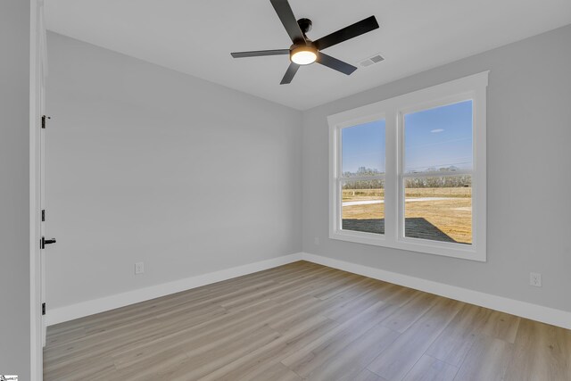 empty room with baseboards, a ceiling fan, visible vents, and light wood-style floors