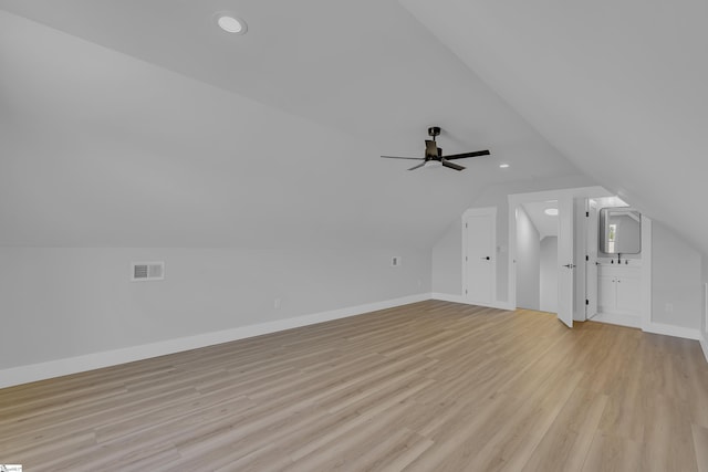 additional living space with visible vents, light wood-style floors, vaulted ceiling, ceiling fan, and baseboards