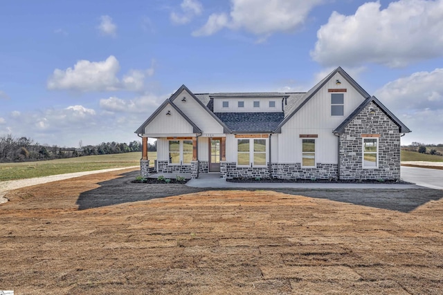 view of front of property featuring stone siding, board and batten siding, and roof with shingles