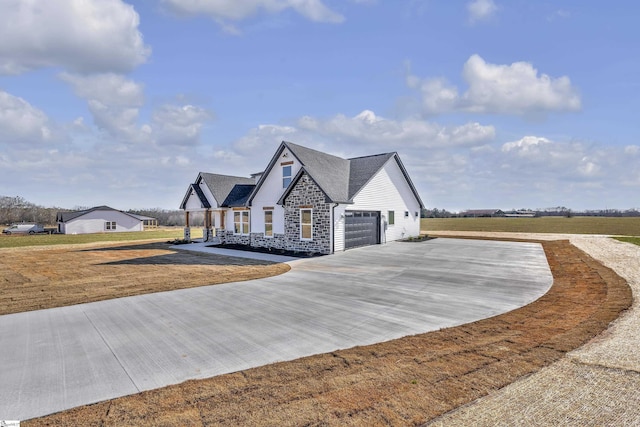 view of front of home with driveway, stone siding, and a front yard