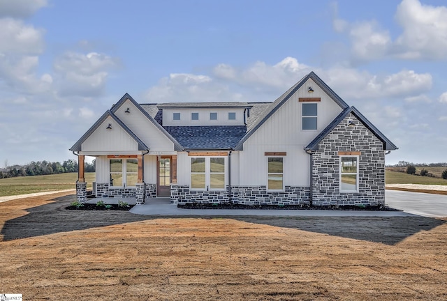 view of front of home with stone siding and roof with shingles