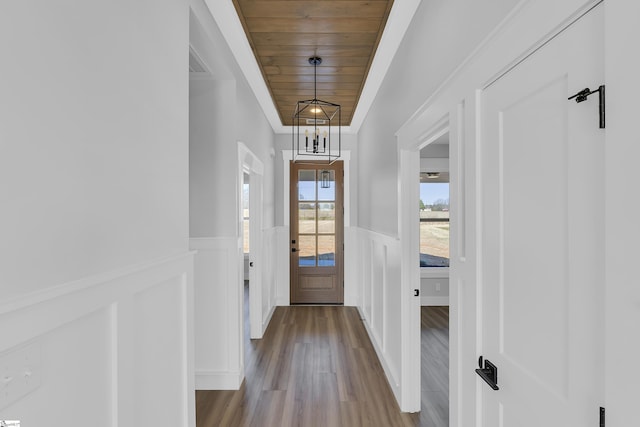 entryway featuring visible vents, wooden ceiling, a wainscoted wall, wood finished floors, and a notable chandelier