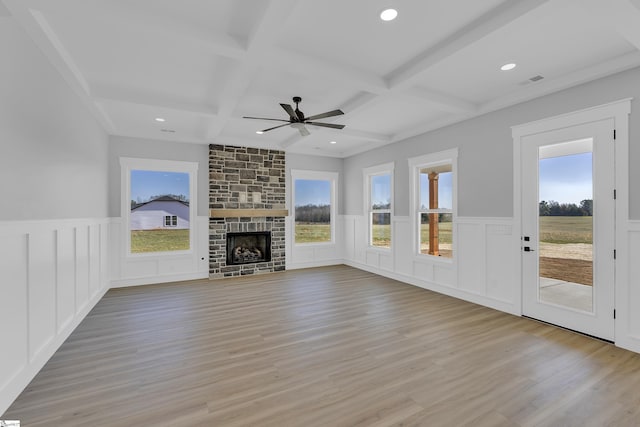 unfurnished living room featuring light wood-type flooring, a large fireplace, coffered ceiling, and beam ceiling