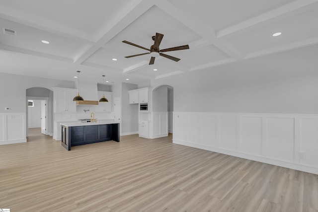 interior space with arched walkways, beam ceiling, light wood-type flooring, and visible vents