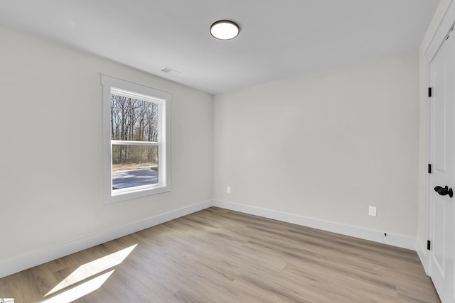 spare room featuring visible vents, light wood-style flooring, and baseboards