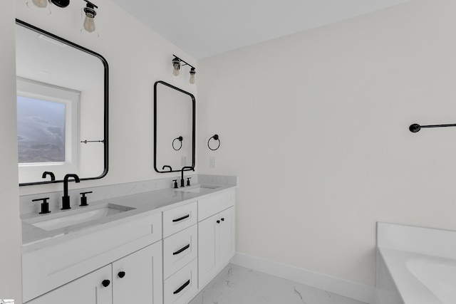 bathroom featuring marble finish floor, double vanity, a sink, and baseboards