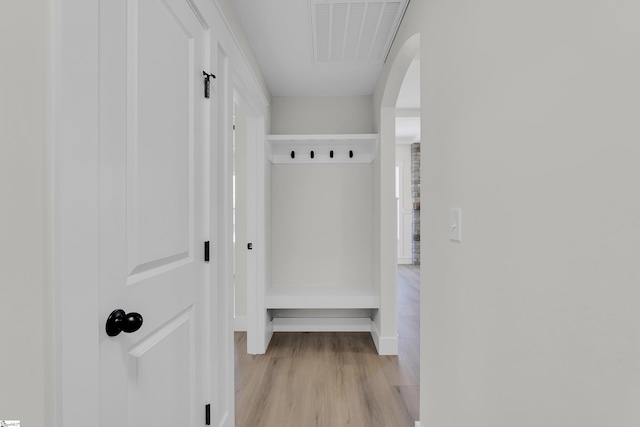 mudroom with light wood-style flooring, visible vents, arched walkways, and baseboards