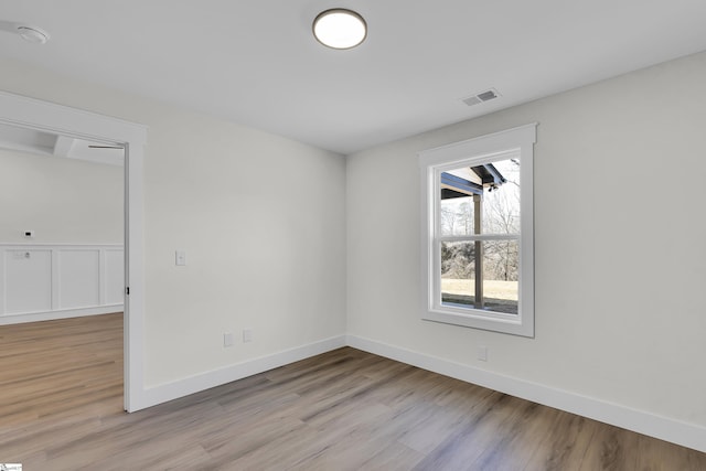 empty room with light wood-type flooring, baseboards, and visible vents