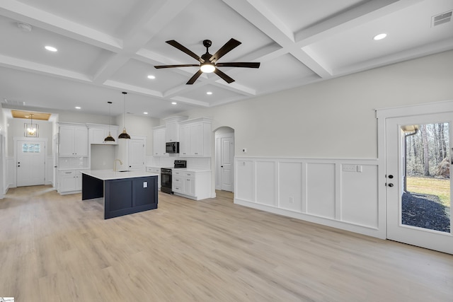 kitchen featuring visible vents, arched walkways, open floor plan, a kitchen island with sink, and black appliances