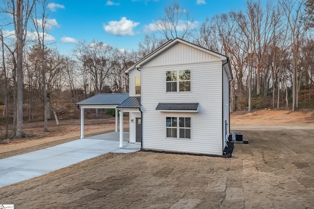 modern farmhouse with metal roof, central AC unit, driveway, a carport, and a standing seam roof