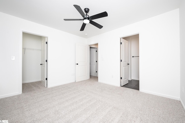 unfurnished bedroom featuring a spacious closet, baseboards, and carpet flooring