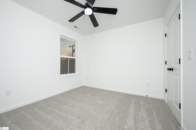 carpeted spare room with visible vents, a ceiling fan, and baseboards