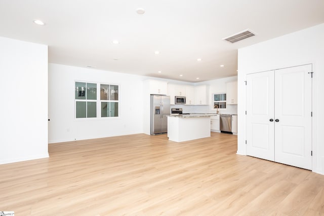 kitchen with light wood finished floors, visible vents, white cabinets, a kitchen island, and stainless steel appliances