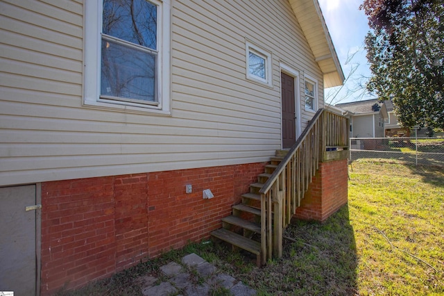 view of side of home with crawl space, stairway, fence, and a lawn