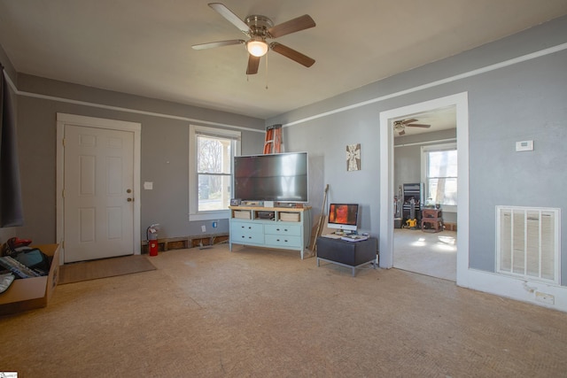 unfurnished living room featuring light carpet, ceiling fan, plenty of natural light, and visible vents