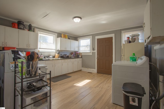 kitchen featuring washer / dryer, white cabinetry, light wood-style floors, and baseboards