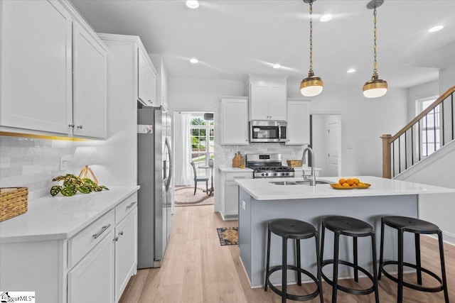 kitchen with a breakfast bar area, appliances with stainless steel finishes, light countertops, and a sink