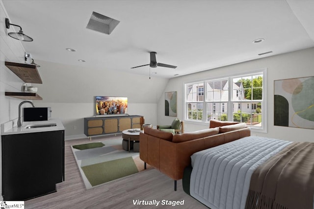 bedroom with lofted ceiling, visible vents, light wood-style floors, a ceiling fan, and a sink