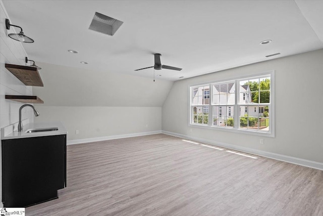 bonus room with lofted ceiling, light wood-style flooring, baseboards, and a sink