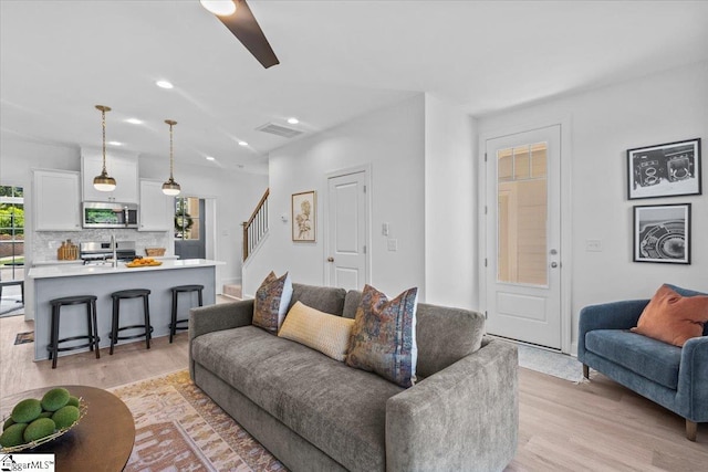 living area with recessed lighting, visible vents, stairway, light wood-style flooring, and a ceiling fan