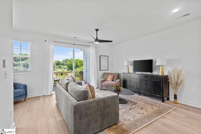 living room featuring plenty of natural light, wood finished floors, visible vents, and baseboards