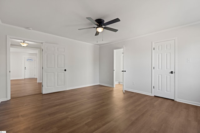 spare room with dark wood-style floors, crown molding, and baseboards