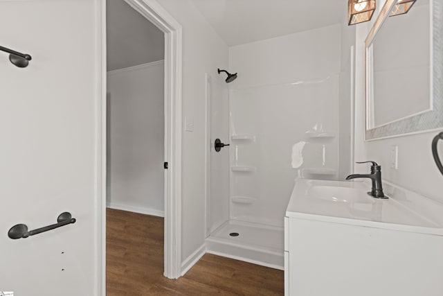 bathroom with baseboards, walk in shower, wood finished floors, and vanity