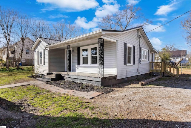 view of front of home with covered porch, dirt driveway, and metal roof