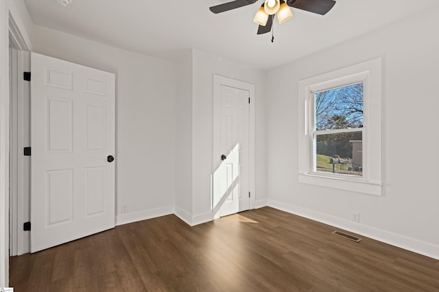 unfurnished bedroom featuring a ceiling fan, visible vents, baseboards, and dark wood-type flooring