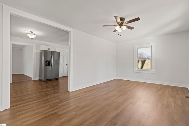 empty room featuring ceiling fan, baseboards, and wood finished floors