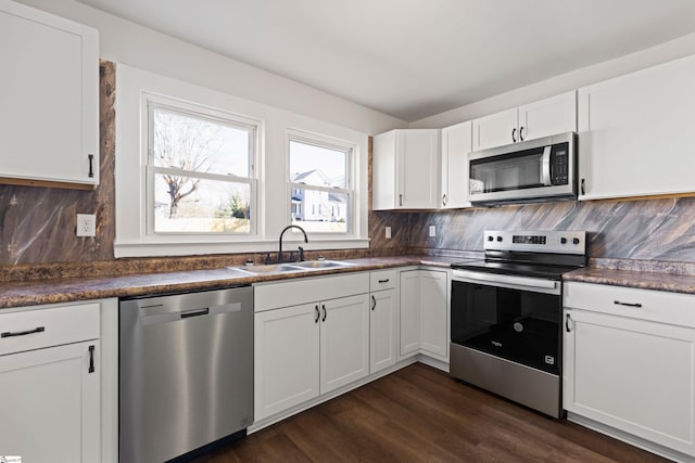 kitchen featuring dark countertops, backsplash, stainless steel appliances, and a sink