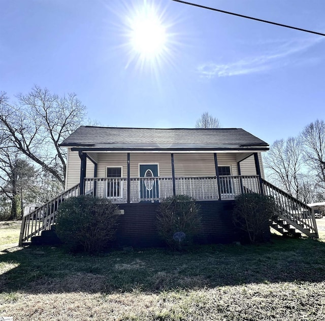 view of front of property with covered porch, a front lawn, and stairway