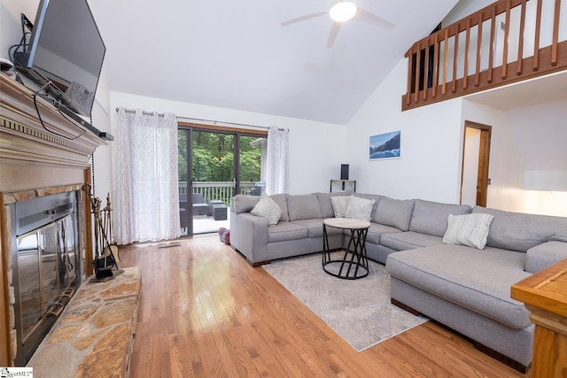 living area with high vaulted ceiling, wood finished floors, a glass covered fireplace, and a ceiling fan