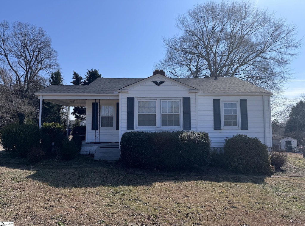 bungalow-style house with a chimney, a front lawn, and roof with shingles