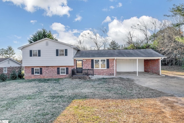 tri-level home with a carport, brick siding, a front yard, and driveway