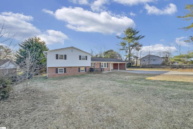 back of property featuring an attached carport, brick siding, a lawn, and driveway