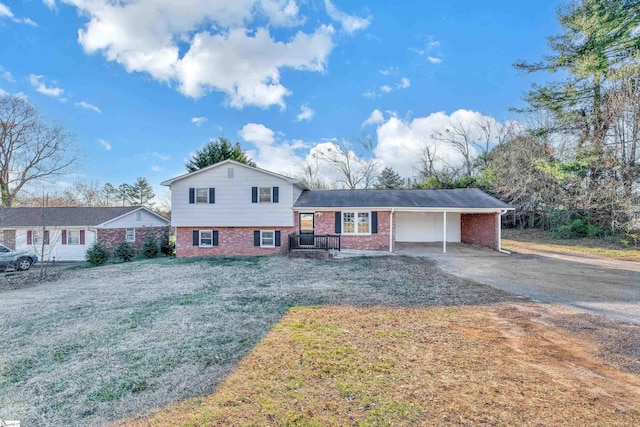 split level home with a carport, driveway, brick siding, and a front lawn