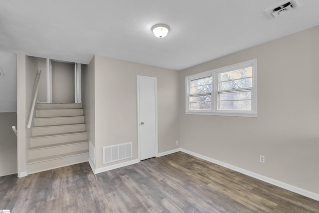 unfurnished room with stairs, wood finished floors, visible vents, and baseboards