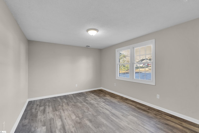 empty room featuring a textured ceiling, baseboards, and wood finished floors