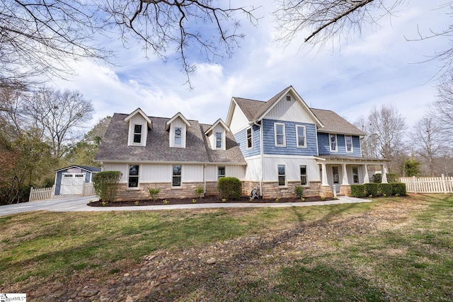 view of front of home with stone siding, a front yard, fence, and an outbuilding