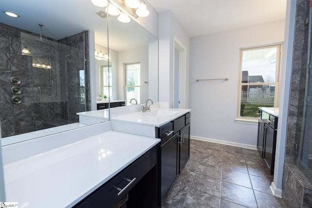 bathroom featuring tiled shower, vanity, visible vents, and baseboards