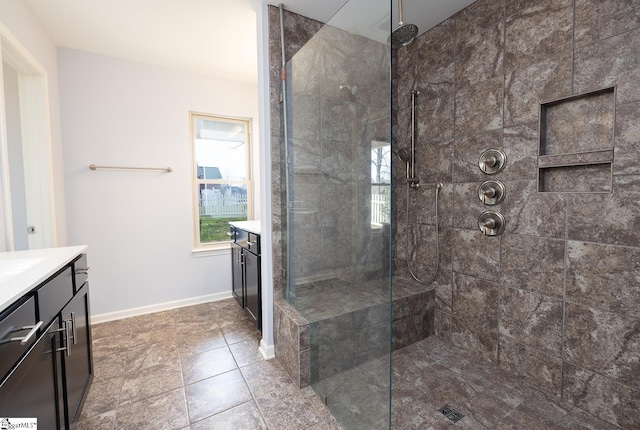 full bathroom with a walk in shower, vanity, and baseboards