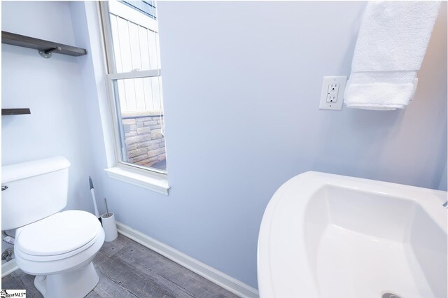 bathroom with baseboards, a sink, toilet, and wood finished floors