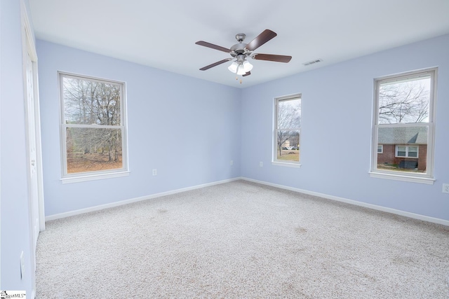 empty room with carpet floors, visible vents, baseboards, and a ceiling fan