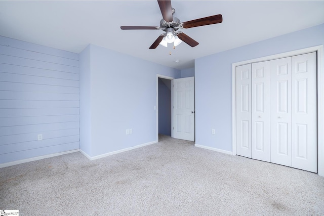 unfurnished bedroom with wood walls, a closet, baseboards, and carpet flooring